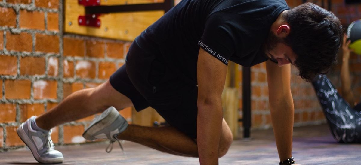 Man working out indoors, performing push-up exercise against a brick wall.